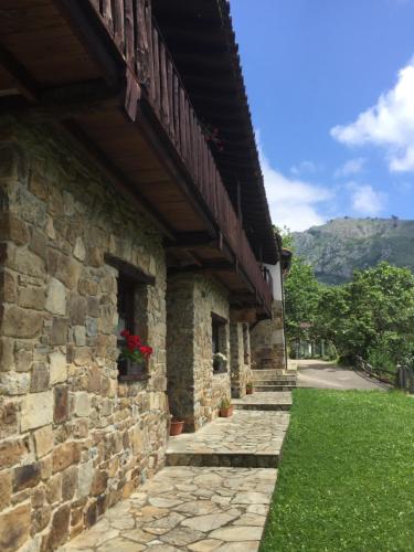 a stone building with a balcony and a green lawn at La Xamoca Apartamentos Rurales in Campiellos
