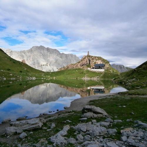 a reflection of a house in a lake in the mountains at Schloss Manndorf Gästehaus in Kötschach