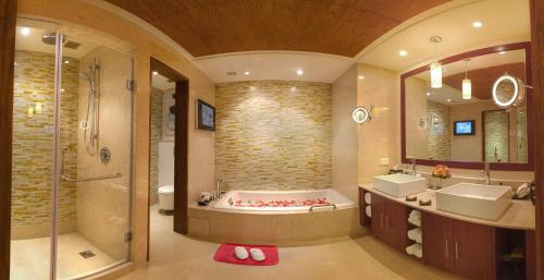 uma casa de banho com uma banheira, 2 lavatórios e um chuveiro em Vivanta Coimbatore em Coimbatore