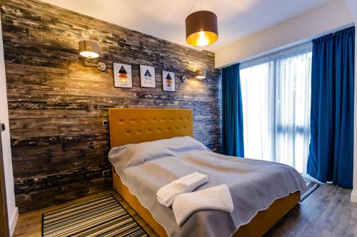 a bedroom with a wooden accent wall and a bed at Pine Woods Apartment A27 in Silver Mountain in Poiana Brasov