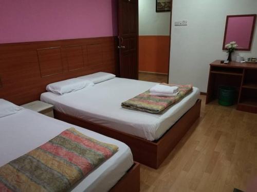 a hotel room with two beds and a mirror at Golden Night Hotel Cameron Highlands in Cameron Highlands