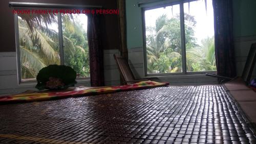 a room with windows and a floor with a rug at mekong floating market Nam Giang homestay in Cai Be