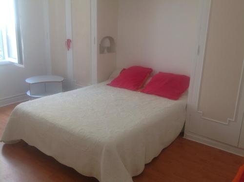 une chambre avec un lit avec deux oreillers rouges dessus dans l'établissement Appartement Tout Confort avec Terrasse, à Nice