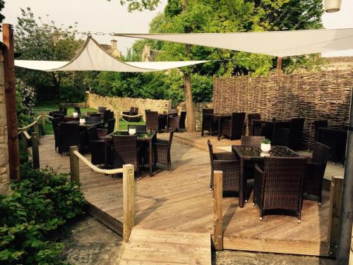 a wooden deck with tables and chairs and a white umbrella at Chester House Hotel in Bourton on the Water