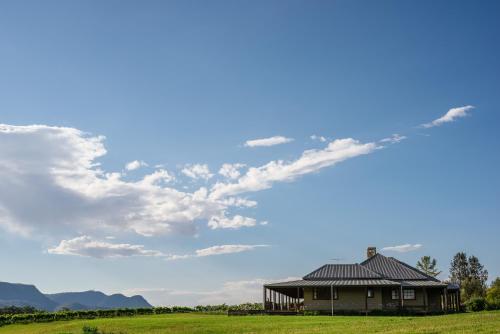 a house in a field under a cloudy sky at Hanging Tree Wines in Pokolbin