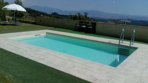 een zwembad met blauw water in een tuin bij Casa Guaitoli in Bagni di Petriolo