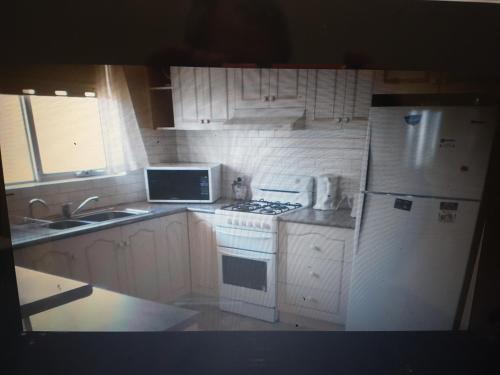 a kitchen with white appliances and a white refrigerator at Glenelg Shores in Adelaide