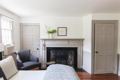 a living room with a fireplace and a chair at Squire Tarbox Inn in Westport