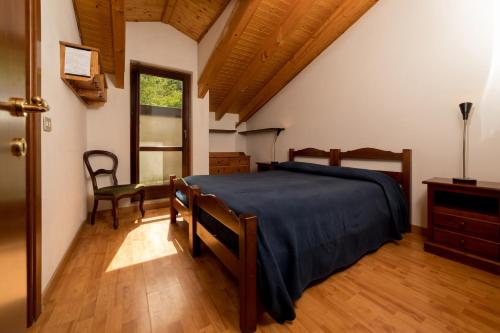 a bedroom with a bed and a chair and a window at Agriturismo Carovane in Compiano