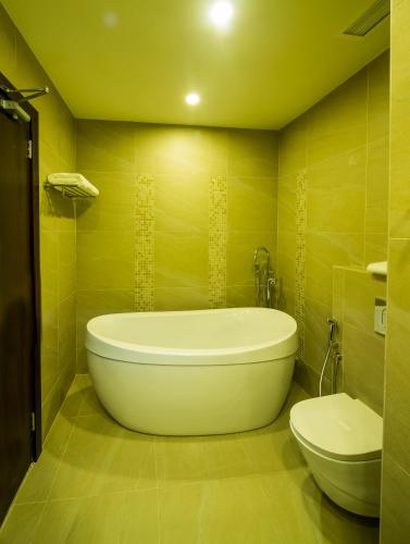 a bathroom with a large tub and a toilet at Arch Hotel in Manama