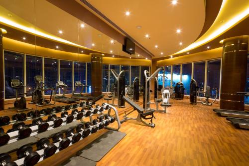a gym with rows of exercise equipment and windows at Arch Hotel in Manama
