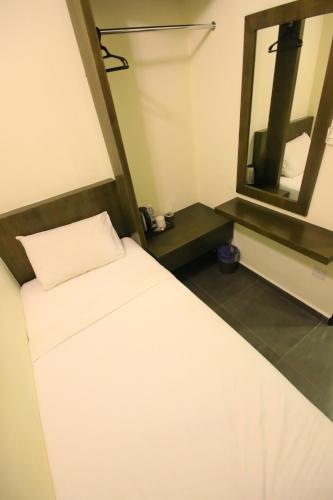 a small room with a bed and a mirror at Marina Oriental Hotel in Butterworth