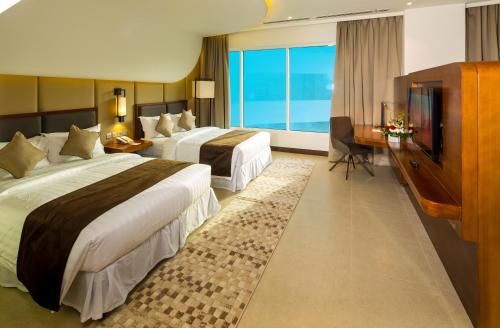 a hotel room with two beds and a television at Arch Hotel in Manama