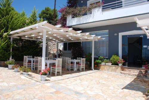 a patio with white chairs under a white pergola at Villa Doka in Sarandë