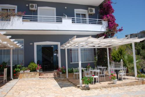 a blue house with white umbrellas and tables and chairs at Villa Doka in Sarandë