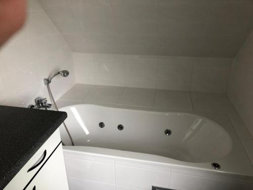 La salle de bains est pourvue d'une baignoire blanche et d'une douche. dans l'établissement FewoJanssen, à Apen