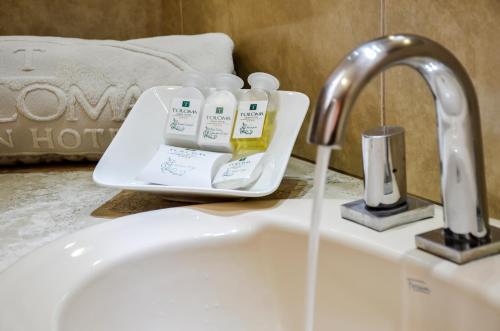 a sink with three bottles of soap and a faucet at Gran Hotel Toloma in Cochabamba