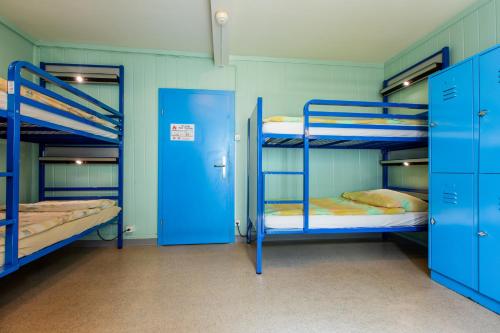 a room with three bunk beds and blue doors at Happy Inn Lodge in Interlaken