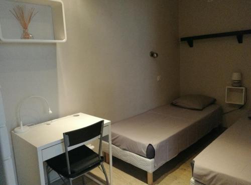 - une petite chambre avec un lit et un bureau dans l'établissement Le Pesquier, à La Ciotat