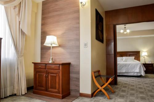 a bedroom with a bed and a table with a lamp at Gran Hotel Toloma in Cochabamba