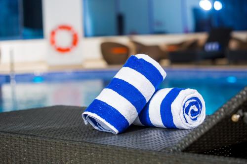 a rolled up towel sitting on a chair next to a pool at Arch Hotel in Manama