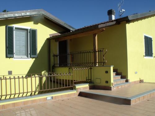 a yellow house with stairs and a balcony at B&B Podere Montese in Villafranca in Lunigiana