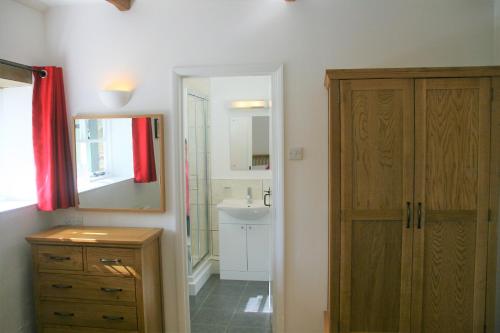 y baño con armario de madera y lavabo. en Glebe House Cottages, en Bude