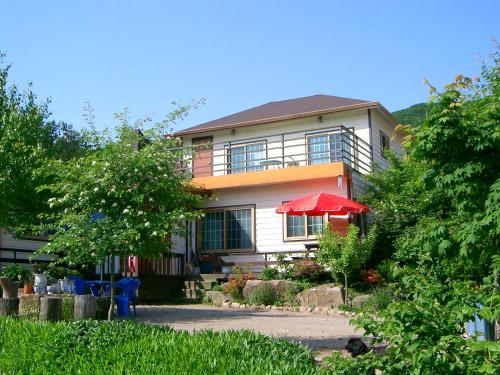 a house with a red umbrella in front of it at Nadeuri Pension in Pyeongchang 