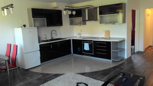 a kitchen with black and white cabinets and a white refrigerator at Apartament w Giżycku przy plaży in Giżycko
