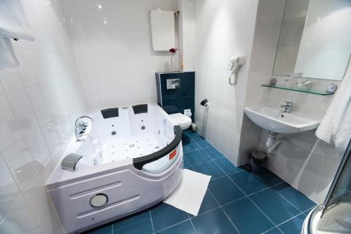 a bathroom with a tub and a toilet and a sink at Hotel Malinowski Business in Gliwice