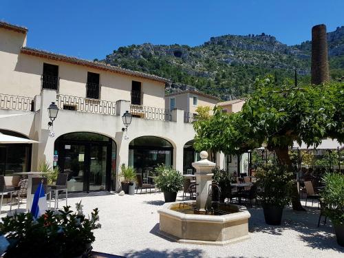 un edificio con una fuente en medio de un patio en Hotel Restaurant du Parc en Bord de Rivière en Fontaine-de-Vaucluse