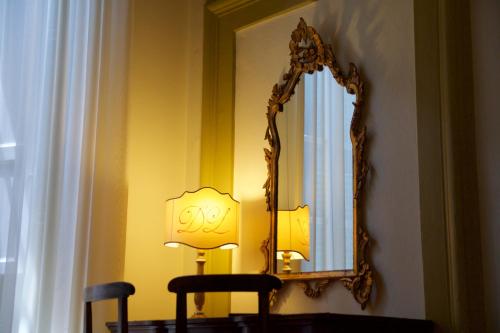 a mirror on a wall next to a table with a lamp at Hotel La Luna in Lucca