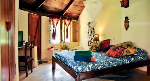 a bedroom with a bed with colorful pillows on it at Ankobra Beach Resort in Axim