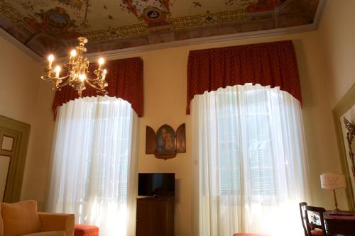 a living room with two windows and a chandelier at Hotel La Luna in Lucca