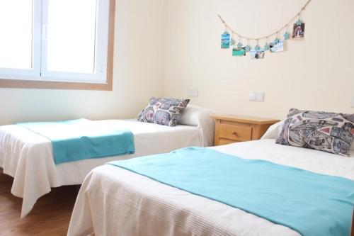 a bedroom with two beds and a window at Mi piso en la ría in Barreiros