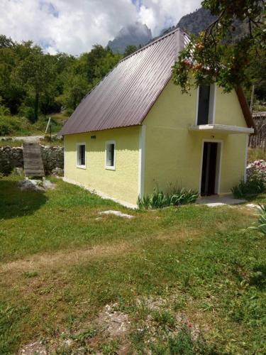 a yellow house with a metal roof on a field at Bujtina Ahmetaj in Valbonë