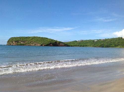 a beach with the ocean and a hill in the background at La Sagesse Hotel, Restaurant and Beach Bar in Content