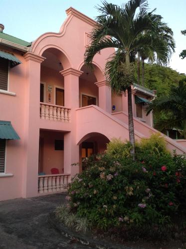 a pink house with a palm tree in front of it at La Sagesse Hotel, Restaurant and Beach Bar in Content