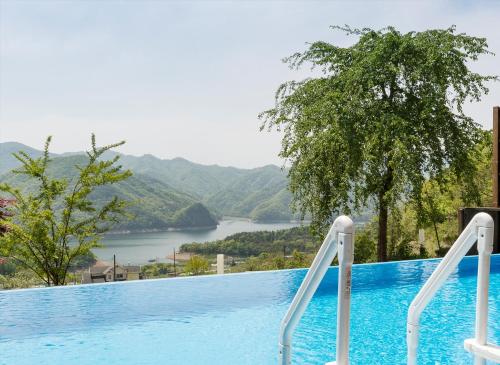 a swimming pool with a view of a river and mountains at Penatess Pool Villa in Chungju
