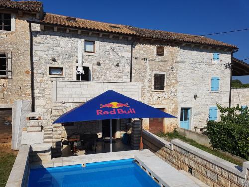 a blue umbrella with a pool in front of a building at Stone House Istria HRIS 1 in Baderna
