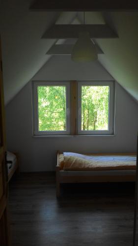 1 dormitorio con 2 ventanas en un ático en Domek Letniskowy przy lesie, en Kruklanki