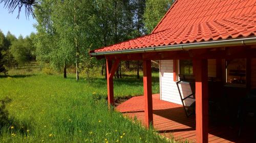 a red house with a red roof on a green field at Domek Letniskowy przy lesie in Kruklanki