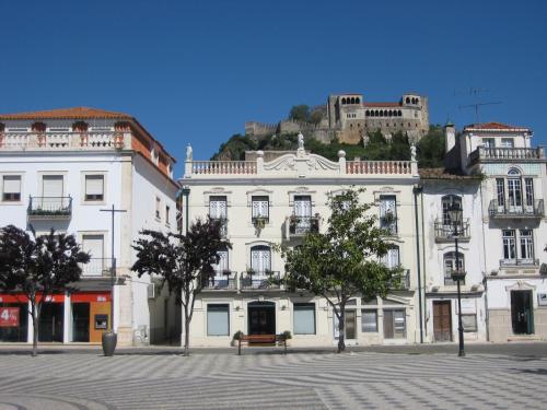 a white building with a castle on top of it at Guest House Eça - Centro Histórico Leiria in Leiria