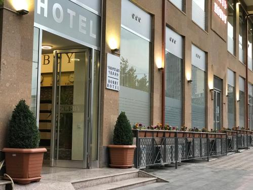 a hotel building with two potted trees in front of it at Hobby Hotel in Yerevan