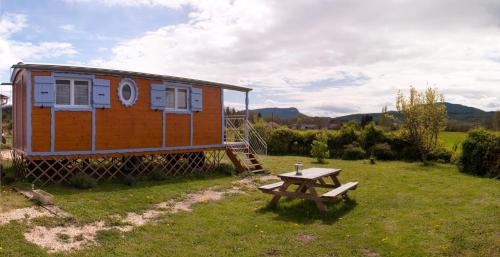 a tiny house with a picnic table in the yard at Chambres d'hôtes La Prairie in Belley