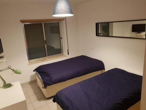 ポルティマンにあるEncosta da Marina Holidaysのベッドルーム1室(ベッド2台、窓、ランプ付)