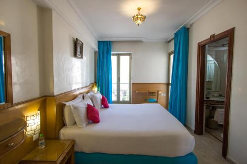 a bedroom with a large white bed with blue curtains at Zahrat Al Jabal in Fès