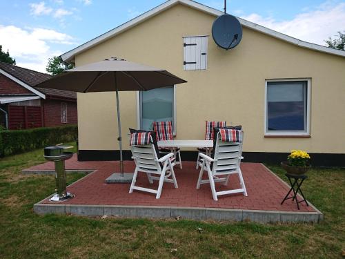 a table with chairs and an umbrella in front of a house at Zur alten Schmiede in Ladelund