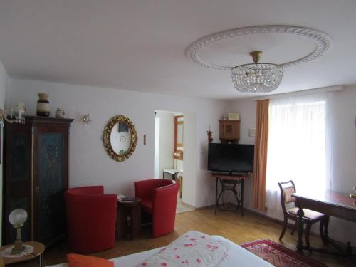 a living room with red chairs and a chandelier at Villa Kreuthhof Appartements in Klosterneuburg