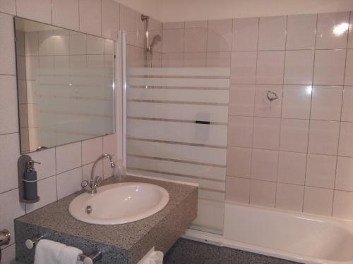 W łazience znajduje się umywalka, prysznic i wanna. w obiekcie Maison Legate "Hôtel Le Baudiere & Spa" w mieście Saint-Beauzire